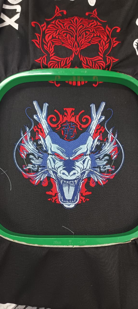 Blue and red dragon head embroidery in a hoop on black fabric